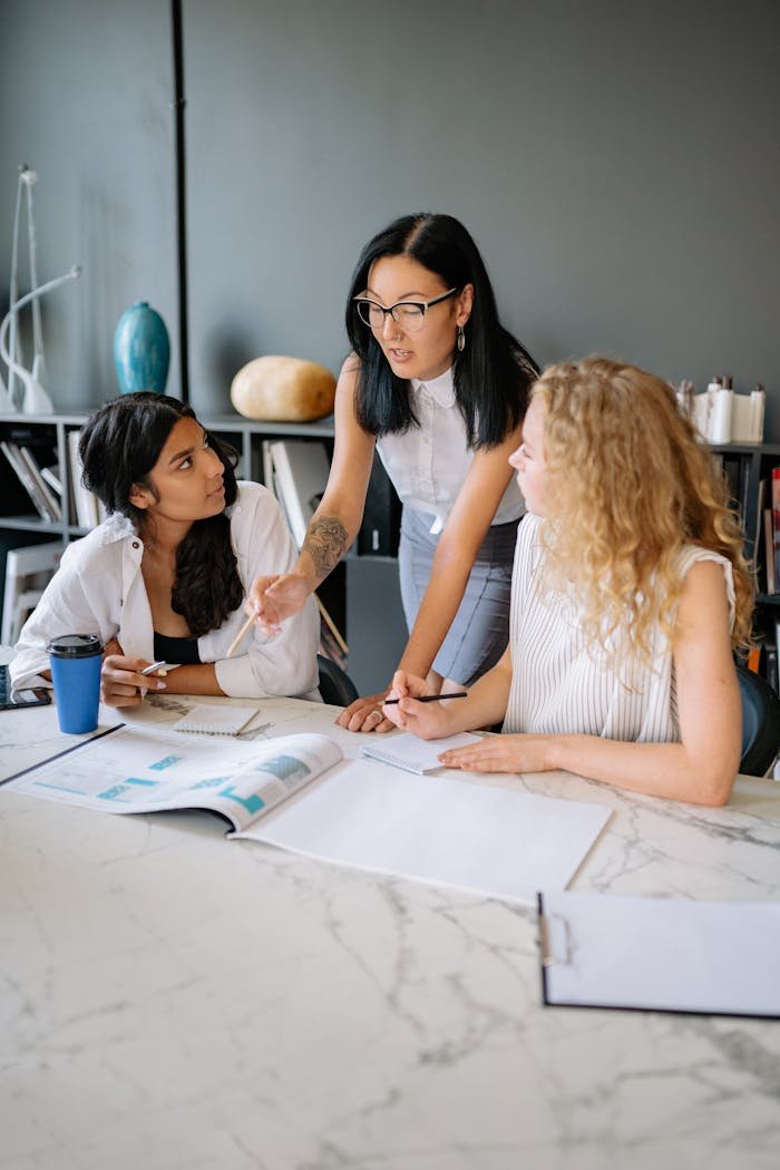 Three diverse businesswomen engaged in a collaborative office meeting, discussing plans and ideas.